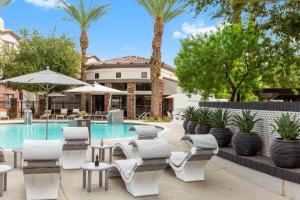 a pool with chaise lounge chairs and tables and a swimming pool at CozySuites Glendale by the stadium with pool 10 in Glendale