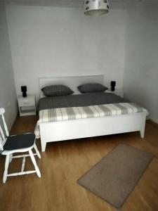 a bedroom with a white bed and a chair at Holiday Home Nena in Drniš