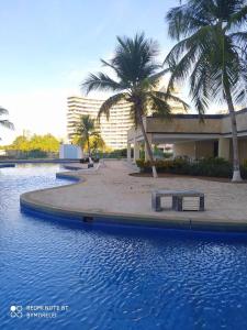 a swimming pool with palm trees in front of a building at Ocean Blue in Porlamar
