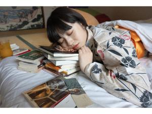 Una chica acostada en una cama con un montón de libros en The Ryokan Tokyo Yugawara - Vacation STAY 21489v en Miyakami