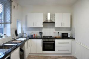 La cuisine est équipée de placards blancs et d'un four avec plaques de cuisson. dans l'établissement Middleton, Manchester, à Middleton