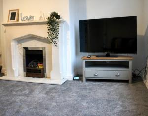 ein Wohnzimmer mit einem TV und einem Kamin in der Unterkunft Middleton, Manchester in Middleton
