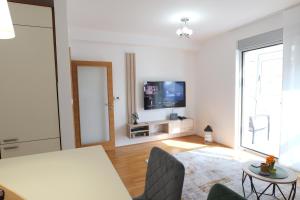 a white living room with a television and a table at Apartman Tina ***** s jacuzzijem u blizini Parka prirode Papuk in Slatina