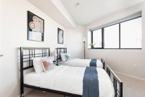 two beds in a white room with a window at Upscale 3BR Penthouse by CozySuites in Indianapolis
