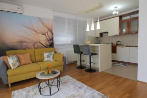 a living room with a yellow couch and a kitchen at Apartman Tina ***** s jacuzzijem u blizini Parka prirode Papuk in Slatina