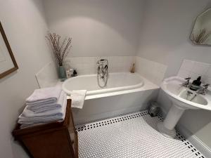 Baño blanco con bañera y lavamanos en Greenhill Farm Barn B&B, en Sutton under Brailes