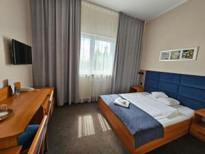 a hotel room with a bed and a desk and a window at Hotel Mikulski in Gliwice