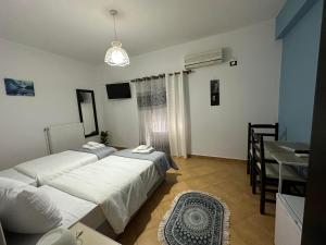 two beds in a room with a table and a dining room at Guest House KrisHen in Përmet