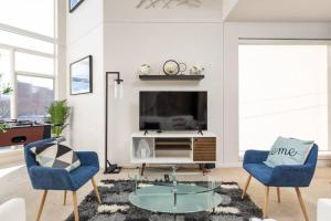 インディアナポリスにあるTWO Modern Penthouses on Mass by CozySuitesのリビングルーム(青い椅子2脚、テレビ付)