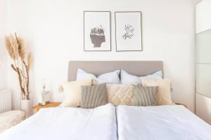 um quarto com uma cama com lençóis brancos e almofadas em TheMarketFlat- Schöne Wohnung im Stadtzentrum em Klagenfurt