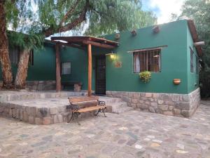 een groen huis met een bankje ervoor bij Cabañas Malka in Tilcara