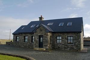 a large stone house with a black roof at Cottage 147 - Renvyle in Renvyle