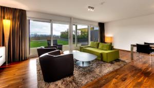 a living room with a green couch and chairs at Wellnesshotel Golfpanorama in Lipperswil
