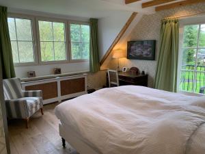 a bedroom with a bed and a desk and windows at Lovely warm Country home in Breukeleveen