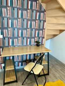 une table et une chaise devant un mur de livres dans l'établissement Maison 3 chambres - 600m Métro Marbrerie - Lille, à Mons-en-Baroeul