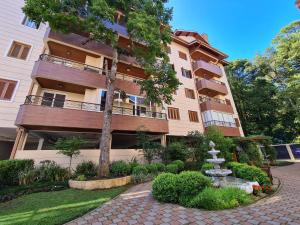 un edificio de apartamentos con una fuente frente a él en 2D no Centro de Gramado, à 500m da Rua Coberta, en Gramado