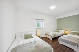 a white room with two beds and a window at Sali Homes - Auszeit am Fuß der Burg Stettenfels in Untergruppenbach