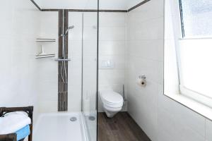 a white bathroom with a toilet and a shower at Backhaus-Wohnung-3 in Bojendorf +3 photos