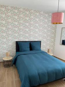 a bed with a blue comforter in a bedroom at Le 202 de la gare: appartement neuf et climatisé in Chalons en Champagne