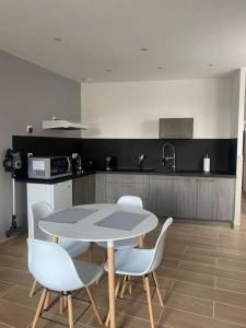 a kitchen with a table and chairs in a room at Le 202 de la gare: appartement neuf et climatisé in Chalons en Champagne