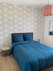 un letto blu in una camera da letto con parete di Le 202 de la gare: appartement neuf et climatisé a Chalons en Champagne