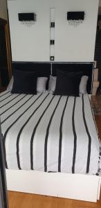Apartamento MarySol B con Terraza y Piscina privada في بينالمادينا: سرير ذو أغطية ومخدات مخططة سوداء وبيضاء