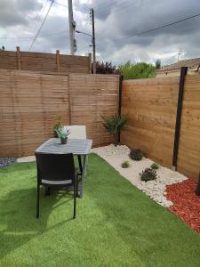 einen Garten mit einem Tisch und einem Zaun in der Unterkunft Appartement neuf avec jardin privatif in Périgueux