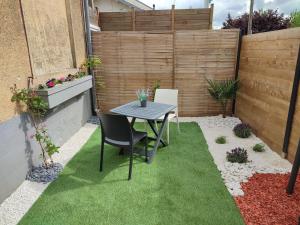 een kleine tuin met een tafel en stoelen op het gras bij Appartement neuf avec jardin privatif in Périgueux