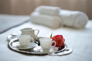 a tray with two cups and a rose on a table at Agriturismo San Francesco in Cortona