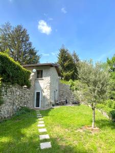 a small stone house with a tree in the yard at La Dimora Degli Olivi Dependance in Galbiate