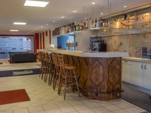 a bar in a restaurant with stools around it at Hotel Adler in Augsburg