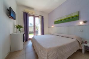 a white bedroom with a bed and a window at Corte dei Melograni Hotel Resort in Otranto