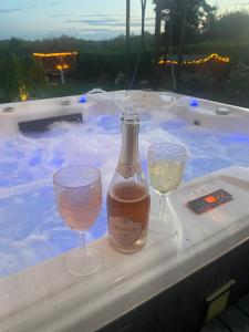 eine Flasche Wein und zwei Gläser auf einer Badewanne in der Unterkunft Stunning guest suite with private hot tub in Rogerstone
