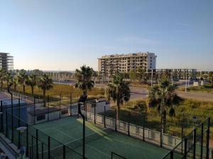 a tennis court with palm trees in a city at Lovely 1bed apartment with padel court near beach in Moncófar