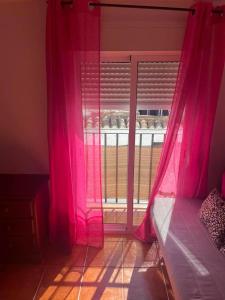 Schlafzimmer mit einem Fenster mit rosa Vorhängen in der Unterkunft Casa Cris in Aracena