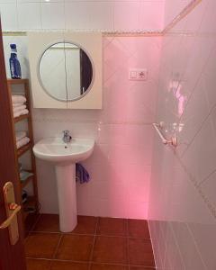 Baño rosa con lavabo y espejo en Casa Cris, en Aracena