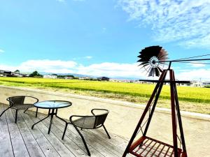 einen Tisch und Stühle auf einer Terrasse mit einer Windmühle in der Unterkunft vintagehouse1925Bali - Vacation STAY 14503 in Nagano