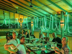 eine Gruppe von Menschen, die an einem Tisch in einem Restaurant sitzen in der Unterkunft Dhooni Finolhu Guesthouse in Maalhos