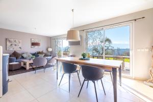 een eetkamer en een woonkamer met een tafel en stoelen bij Villa proche Annecy in Lovagny