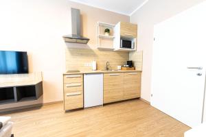 cocina pequeña con armarios de madera y TV en MADU-Living Vienna - Oskar, en Viena