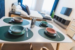 una mesa con platos y cucharas en la sala de estar en MADU-Living Vienna - Oskar, en Viena