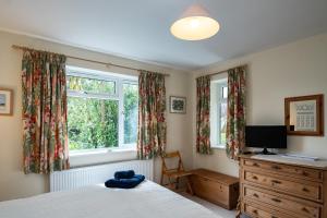 a bedroom with a bed and a dresser and two windows at Pencreek in Padstow