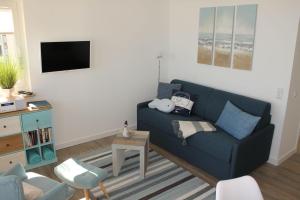 a living room with a blue couch and a tv at Ferienwohnung-Meeresrauschen in Großenbrode