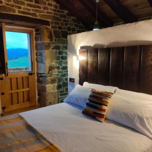 1 dormitorio con 1 cama blanca y ventana en Villa Brenagudina - Cabaña Pasiega con piscina climatizada, en San Pedro del Romeral