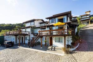 uma grande casa com uma varanda e um guarda-chuva em BZ20 Geribá com vista panorâmica! 6 quartos em Búzios