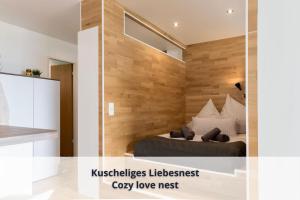 a bedroom with a bed and a wooden wall at Auszeit Apartment ALPENBLICK in Oberteuringen