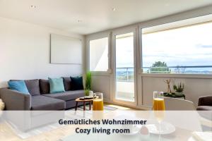 a living room with a couch and a large window at Auszeit Apartment ALPENBLICK in Oberteuringen