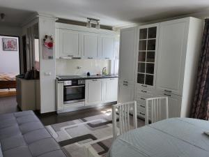 una cucina con armadi bianchi, tavolo e sedie di Apartament Florilor a Baia Mare