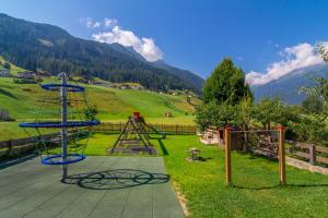 um parque infantil num campo com montanhas ao fundo em Aparthaus Alpenzauber em Neustift im Stubaital