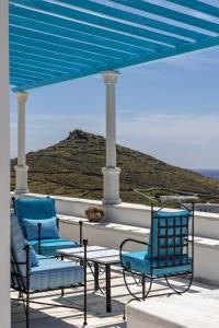 a patio with chairs and a table and a blue umbrella at Marble Villas in Tinos Town